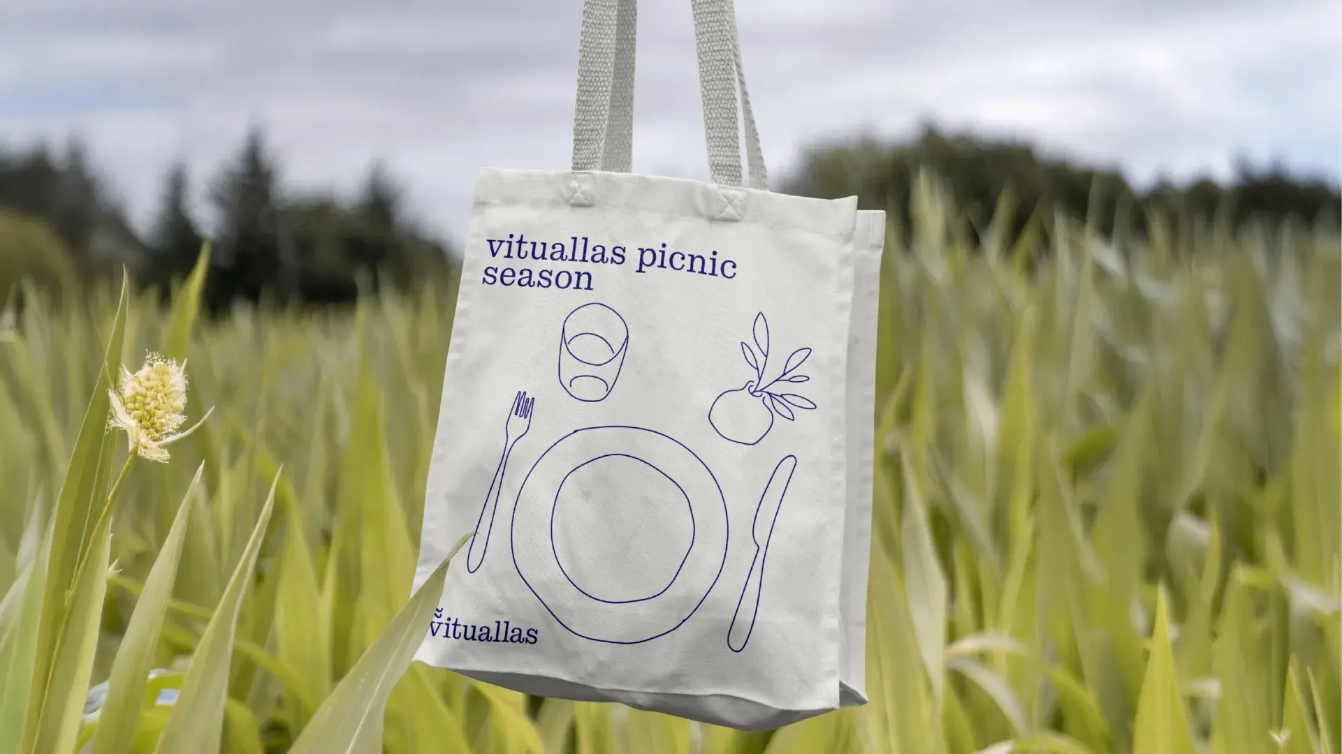 Una bolsa de tela con la marca Vituallas Picnic apoyada sobre la hierba.