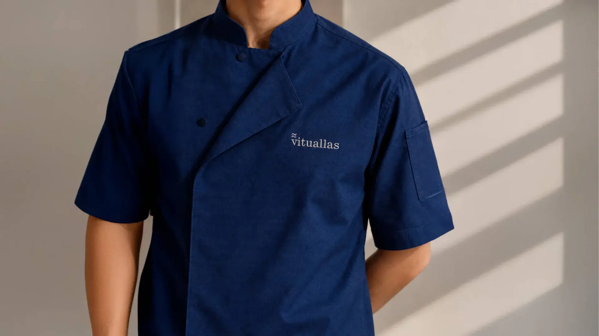 Chaquetilla de cocina azul índigo con el logotipo de Vituallas bordado.